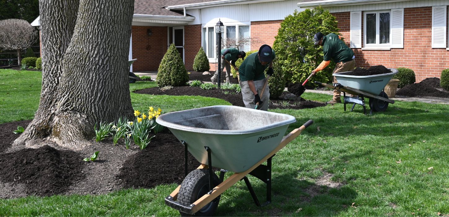 lawn care crew mulching garden beds in spring