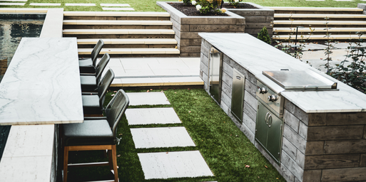 Closeup of pool bar and outdoor kitchen with turf and paver walkway