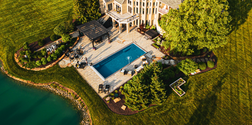 An aerial view of a design build featuring softscaping, pergola, kitchen, firepit, and pool