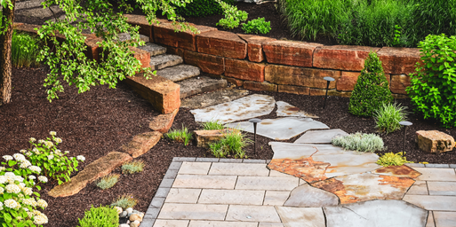 Closeup view of a stone staircase and retaining wall leading down to a natural stone paver pathway
