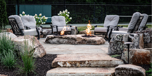 Closeup of a firepit made of boulders surrounded by patio furniture