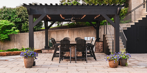 Outdoor kitchen pergola featuring a smoker and bistro lights on a patio