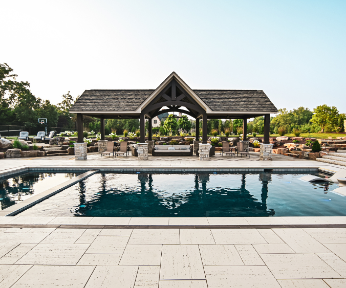 A finished design build project featuring a pergola and pool with a firepit off to the side