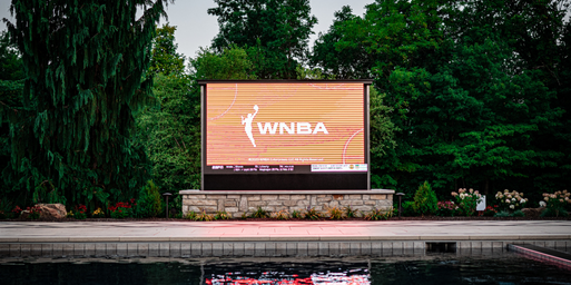 View of an outdoor television beside a pool and surrounded by trees