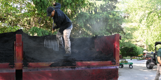 Wasson crew scooping mulch from a truck on a job site