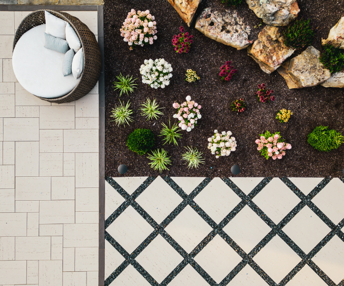 An aerial view of pavers on a patio lined with soft scaping and rocks