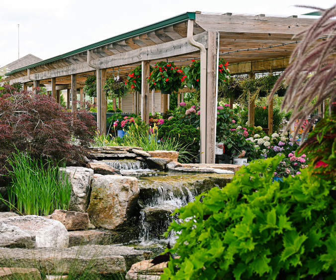 A view of the Wasson Fishers Garden Center showcasing the pergola with hanging baskets and the waterfall