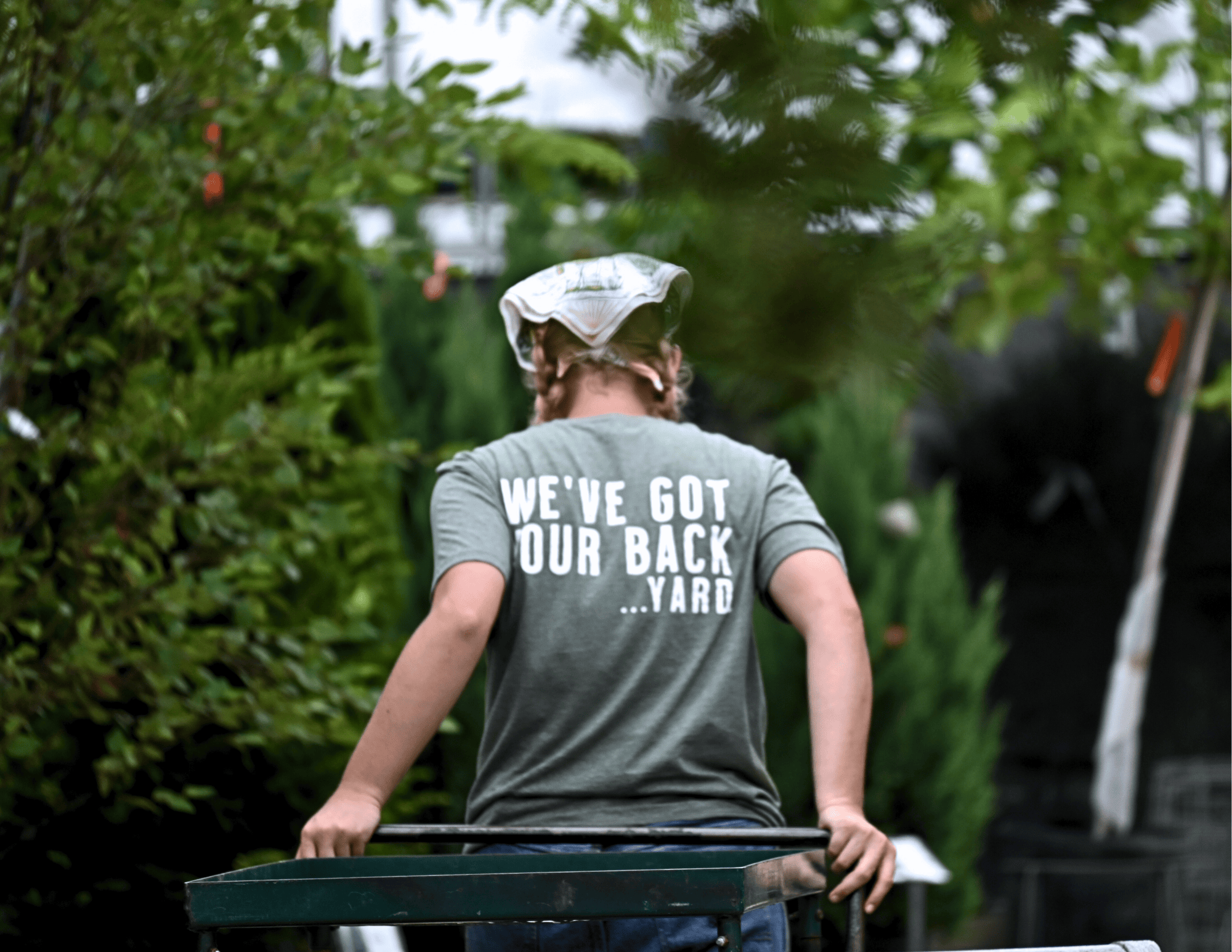 Image of a Wasson Garden Specialist from the back with a company t-shirt that reads "We've got your back...yard."
