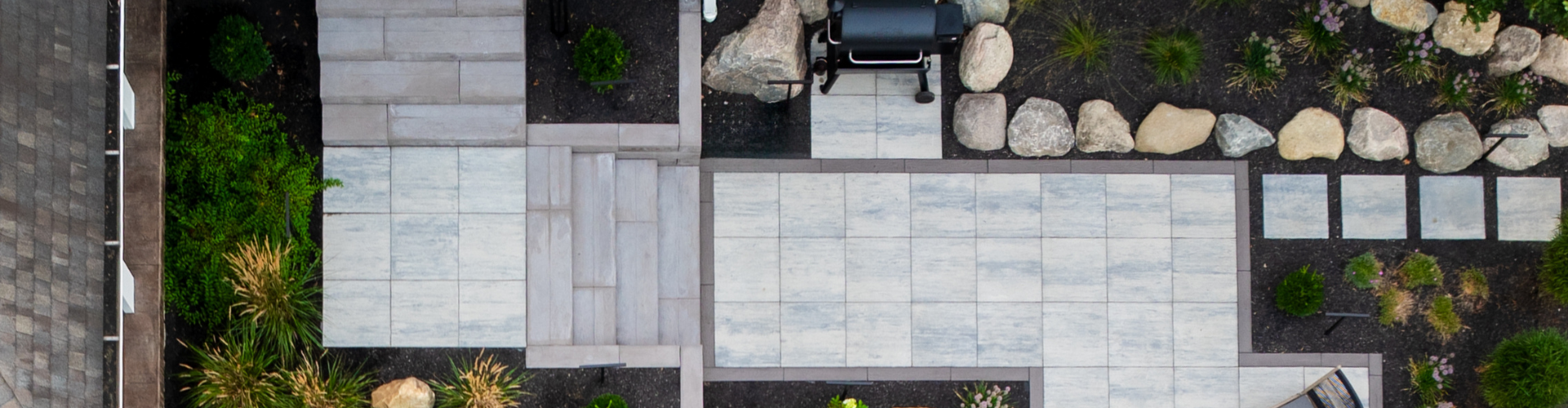 Aerial shot of a hardscape design featuring natural and modern steps to a pathway, lined by raised landscape beds