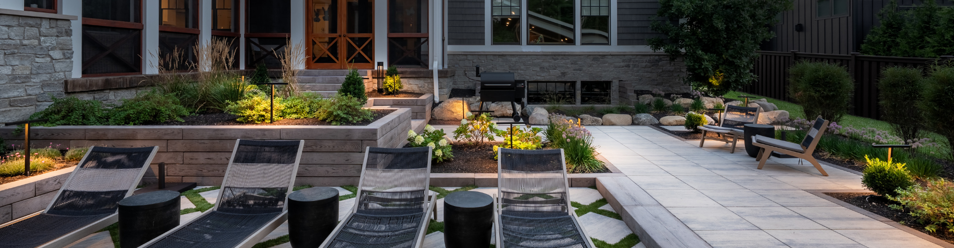 A shot of raised garden beds and stone steps that lead to a paved patio